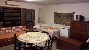 Una habitación pequeña y acogedora con cama, sofá, una mesa redonda y un armario.