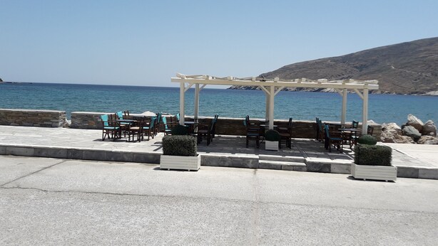 Un patio frente al mar con mobiliario exterior y una pérgola con vistas al océano.