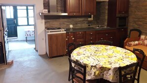 Una cocina compacta con armarios de madera, una estufa a gas y una mesa de comedor con mantel floreado.
