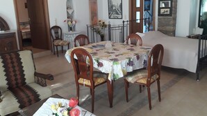 Un comedor con una mesa dispuesta para seis personas, rodeada de sillas de madera. Hay una mesita auxiliar con un jarrón de flores.