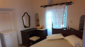Un dormitorio con cama, cómoda, espejo y escritorio pequeño.