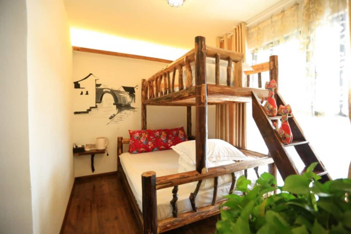 Uma cama beliche com estrutura de madeira e travesseiro estampado com flores vermelhas.