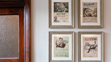 Four framed vintage advertisements for Skype, Facebook, Twitter, and YouTube on a wall.