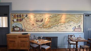Interior de restaurante con un mapa grande en la pared, muebles de madera y un radiador.