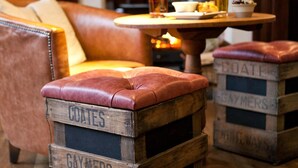 Una habitación acogedora con un sofá de cuero, una mesita de madera con una vela y tres cajas de madera con nombres.