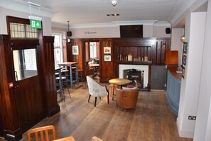 Un interior tradicional con pisos de madera, chimenea, zona de bar y comedor con sillas y mesas.