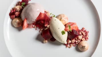 Une assiette de dessert avec une boule de glace, des framboises et une décoration de betterave.