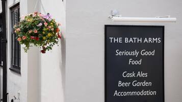 A signboard advertising The Bath Arms, highlighting its offerings such as seriously good food, cask ales, beer garden, and accommodation.