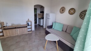 Un espace de vie moderne comprenant un canapé, une petite table et une cuisine en arrière-plan.