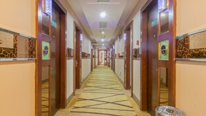 A hotel corridor with wooden doors, a patterned carpet, and a ceiling light. - Sucha Hotel Wuhan Hankou Railway Station (Wuhan)