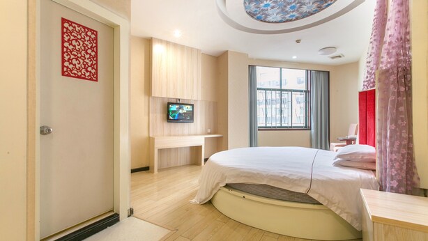 A modern hotel room with a bed, a TV mounted on the wall, a window with curtains, and a decorative red panel on the wall. - Sucha Hotel Wuhan Hankou Railway Station (Wuhan)