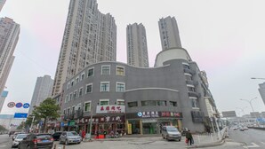 A hotel with a curved facade, multiple windows, and a sign for a local restaurant. - Sucha Hotel Wuhan Hankou Railway Station (Wuhan)