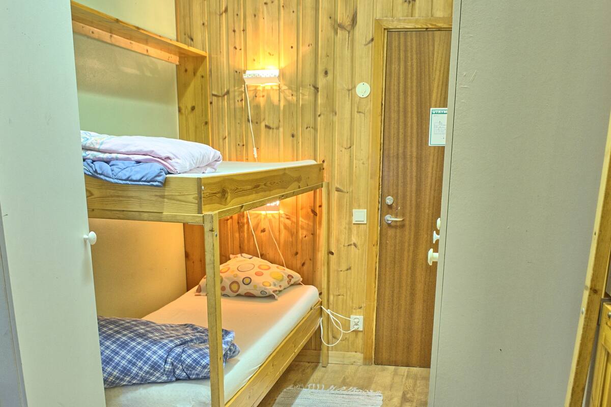 Een kleine kamer met houten stapelbedden en een deur.