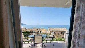 A balcony with a table and chairs, overlooking a coastal view with buildings and the sea. - Corfu Island Apartment 149 (Corfu)