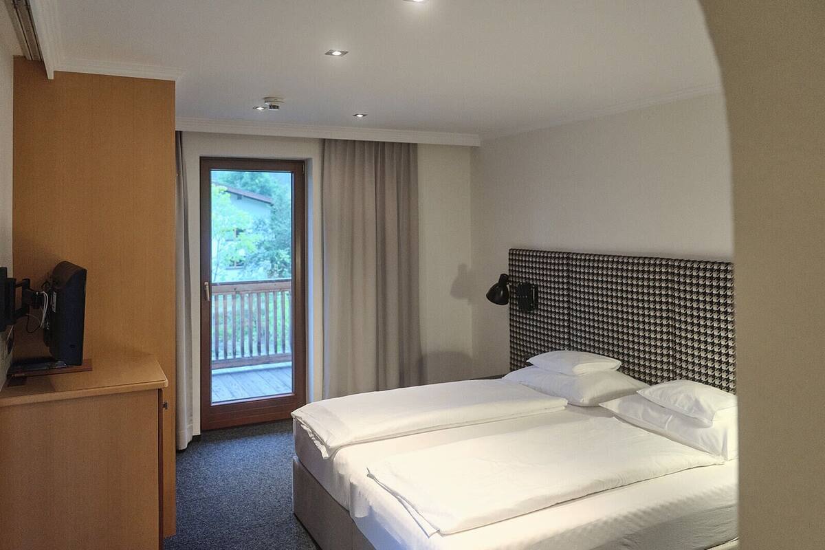 Habitación de hotel con una cama grande, un escritorio y una ventana con cortinas.