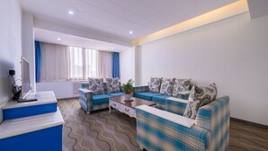 A modern living room with a sofa set, a coffee table, and a television on a stand. - Sucha Hotel Xian Hangtiancheng Station (Xi'an)