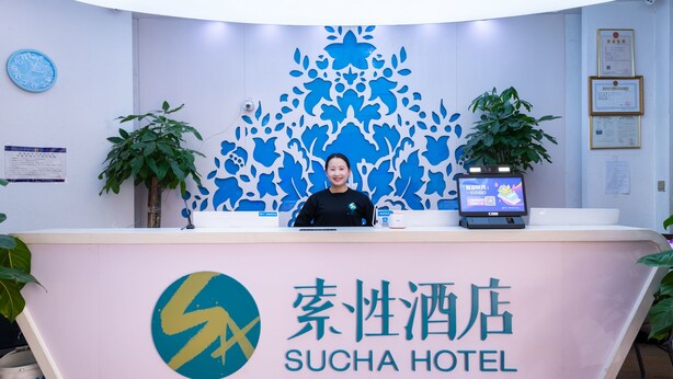 A reception desk at Sucha Hotel with a modern design, a digital screen, and a logo. - Sucha Hotel Xian Hangtiancheng Station (Xi'an)