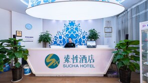 A reception desk at Sucha Hotel with a modern design, including a logo, a clock, and framed certificates on the wall. - Sucha Hotel Xian Hangtiancheng Station (Xi'an)