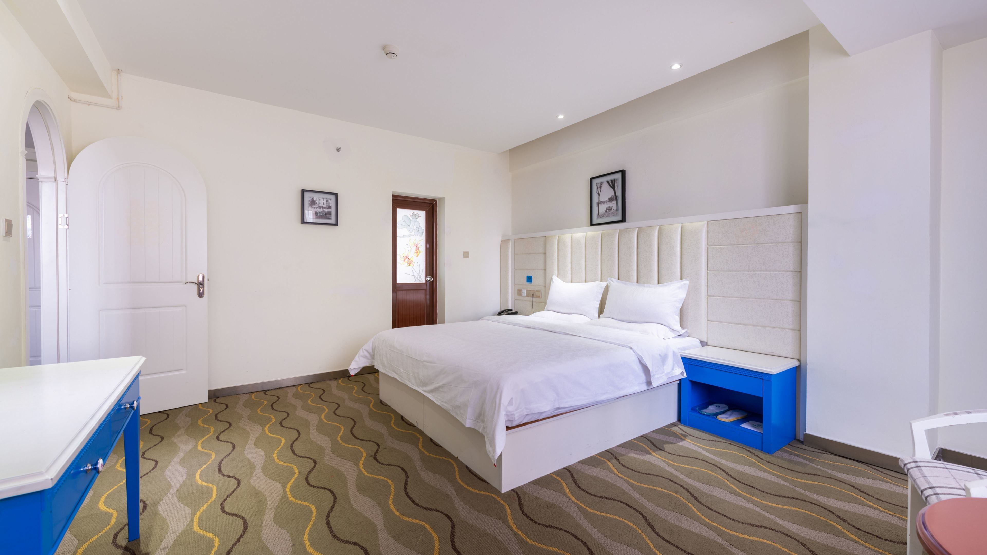 A hotel room with a bed, a bedside table, a chair, a wardrobe, and a door.
