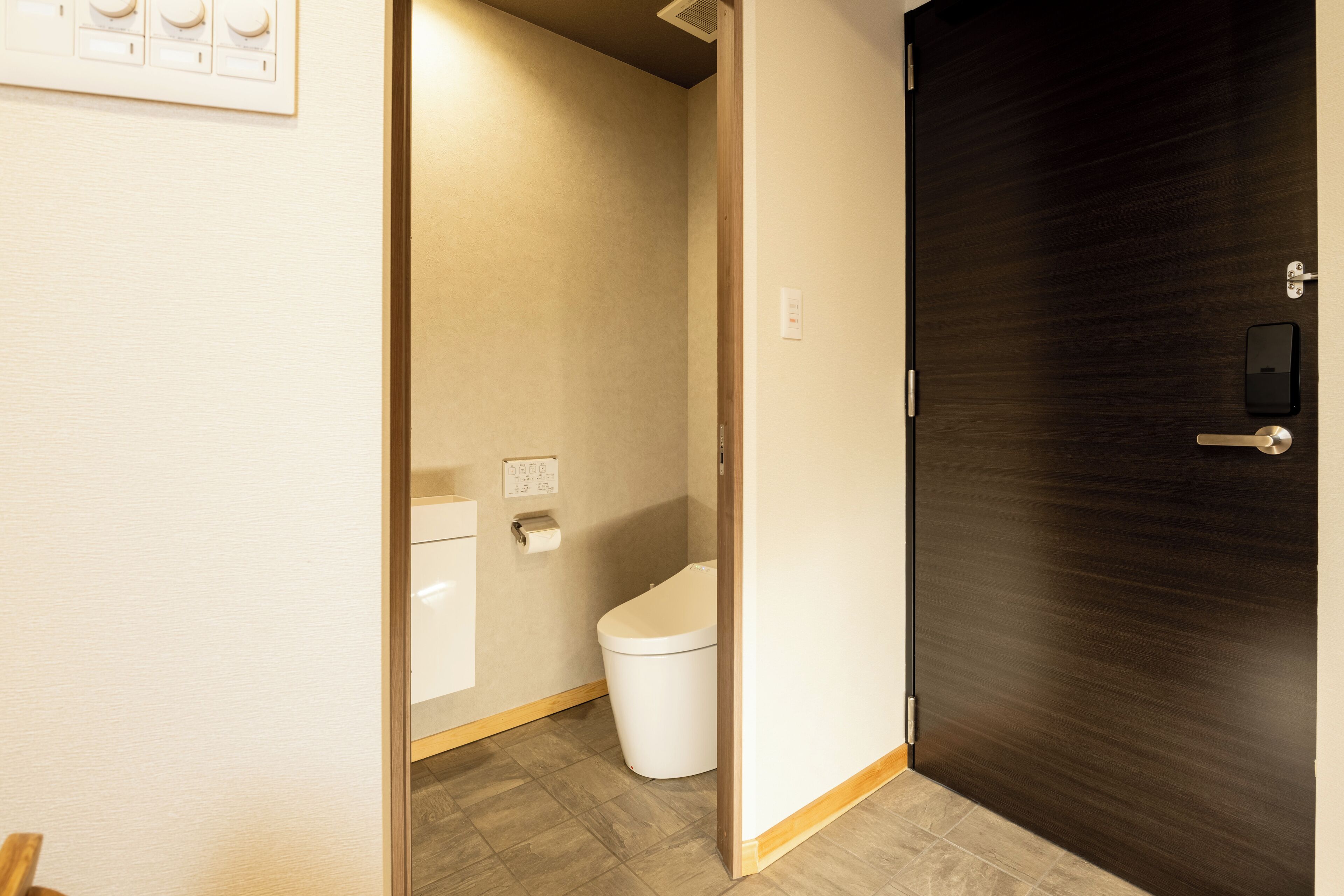 Ein Badezimmer mit Toilette, Handtuchhalter und Holztür.