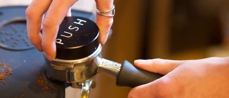 A close-up of a hand operating a coffee machine with a 'PUSH' button.