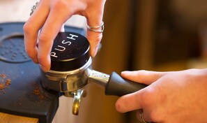 A close-up of a hand operating a coffee machine with a 'PUSH' button. - Tanuki Nozawa (Nozawaonsen)