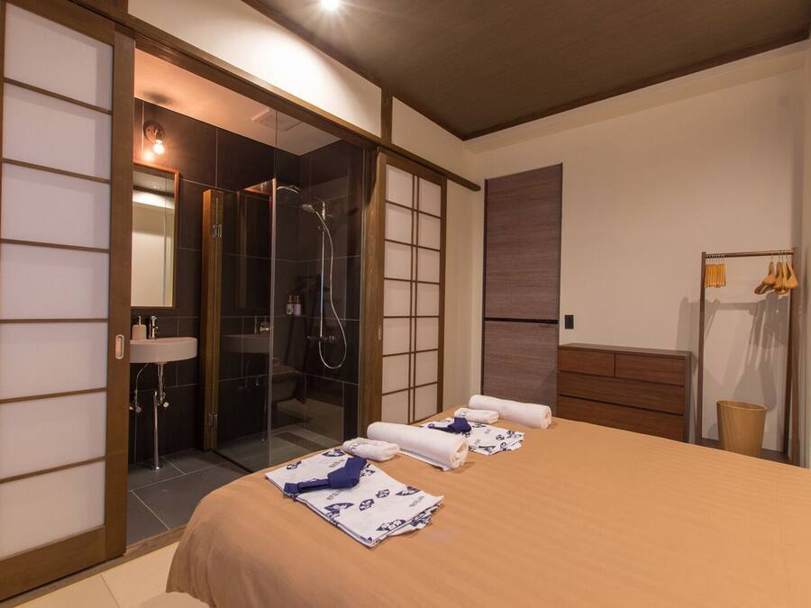 Una habitación de hotel con cama, baño con lavabo y ducha, y un armario.