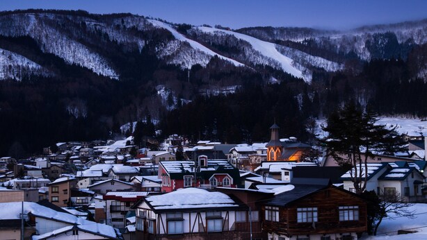 A snow-covered village with traditional buildings and a church. - Tanuki Nozawa (Nozawaonsen)