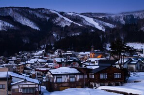 A snow-covered village with traditional buildings and a church. - Tanuki Nozawa (Nozawaonsen)