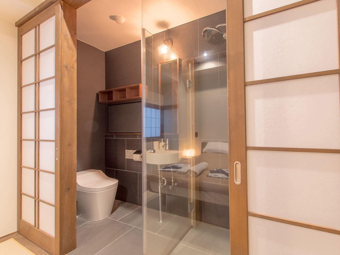 A modern bathroom with a glass-enclosed shower, a toilet, and a sink.