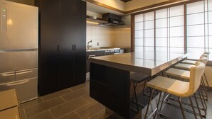 A modern kitchen with a central island, dark cabinetry, and a large window providing natural light. - Tanuki Nozawa (Nozawaonsen)