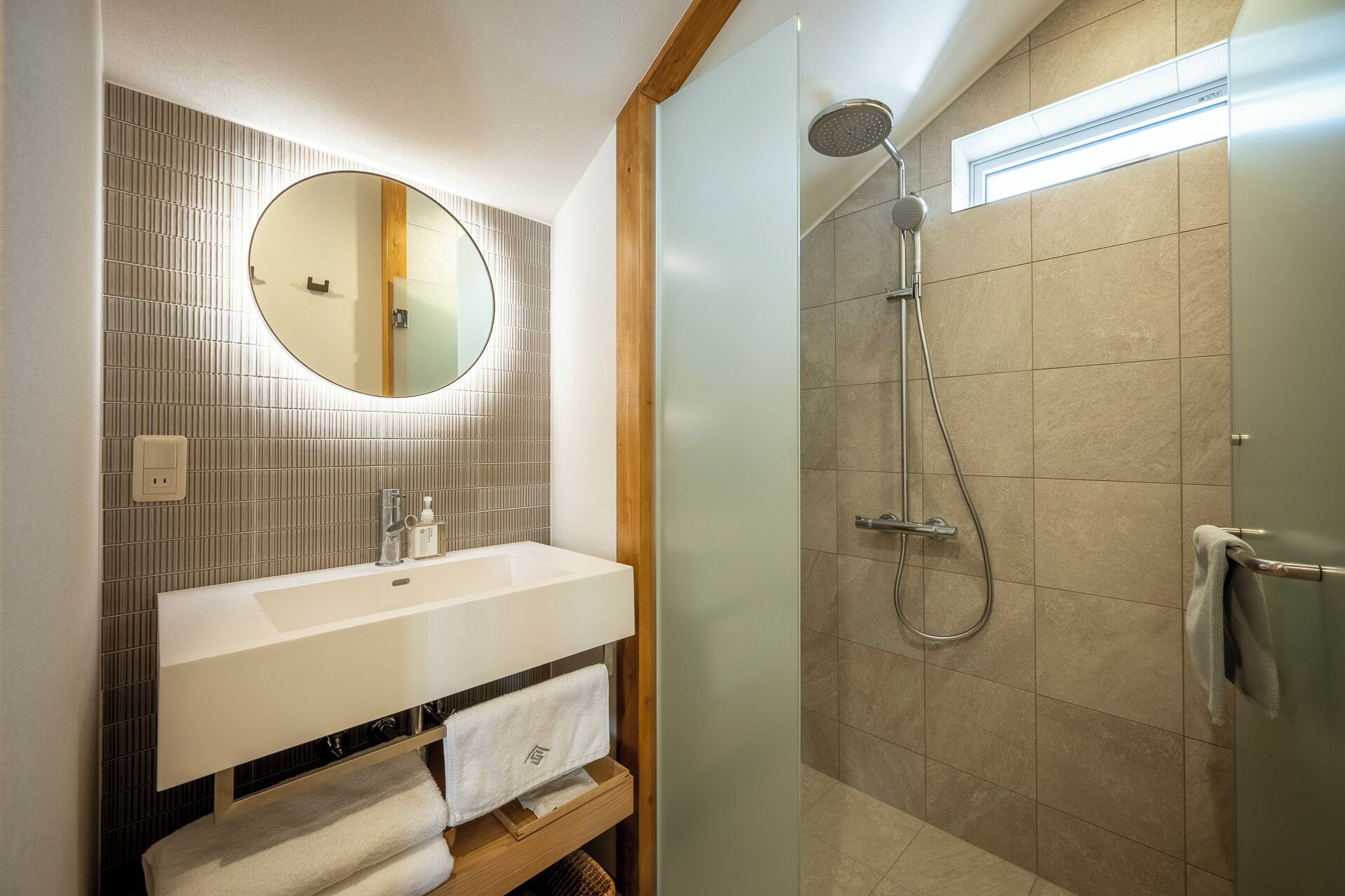 A bathroom with a round mirror, a sink, and a shower.