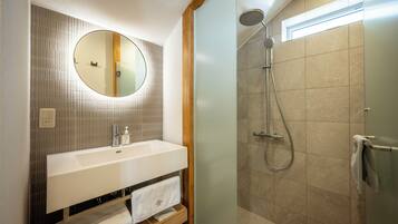 A bathroom with a round mirror, a sink, and a shower.