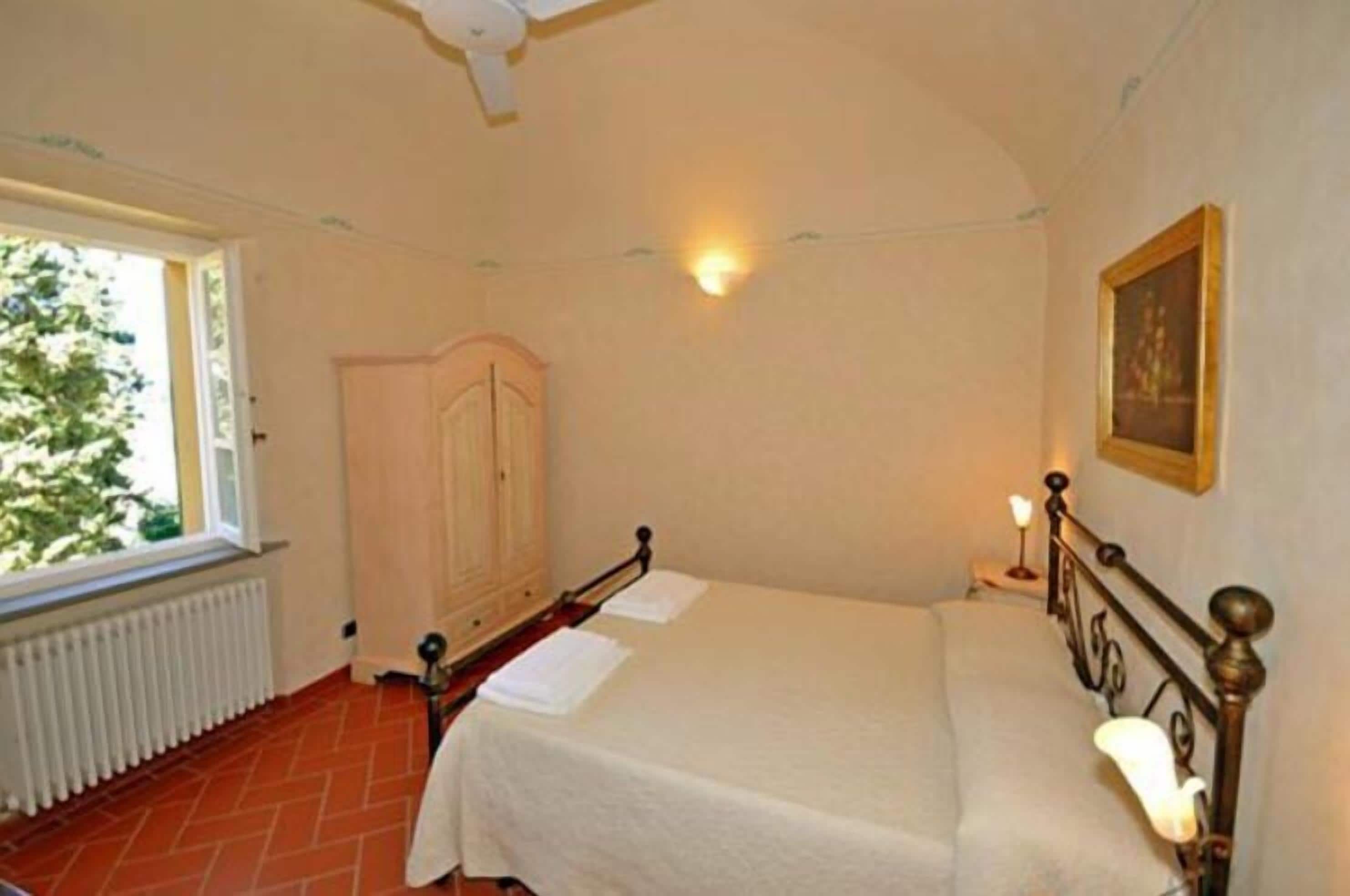 Un dormitorio con cama, armario, radiador y ventana.