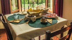 Un tavolo da pranzo con vista su dolci colline verdi, un bicchiere d'acqua e diversi piatti.