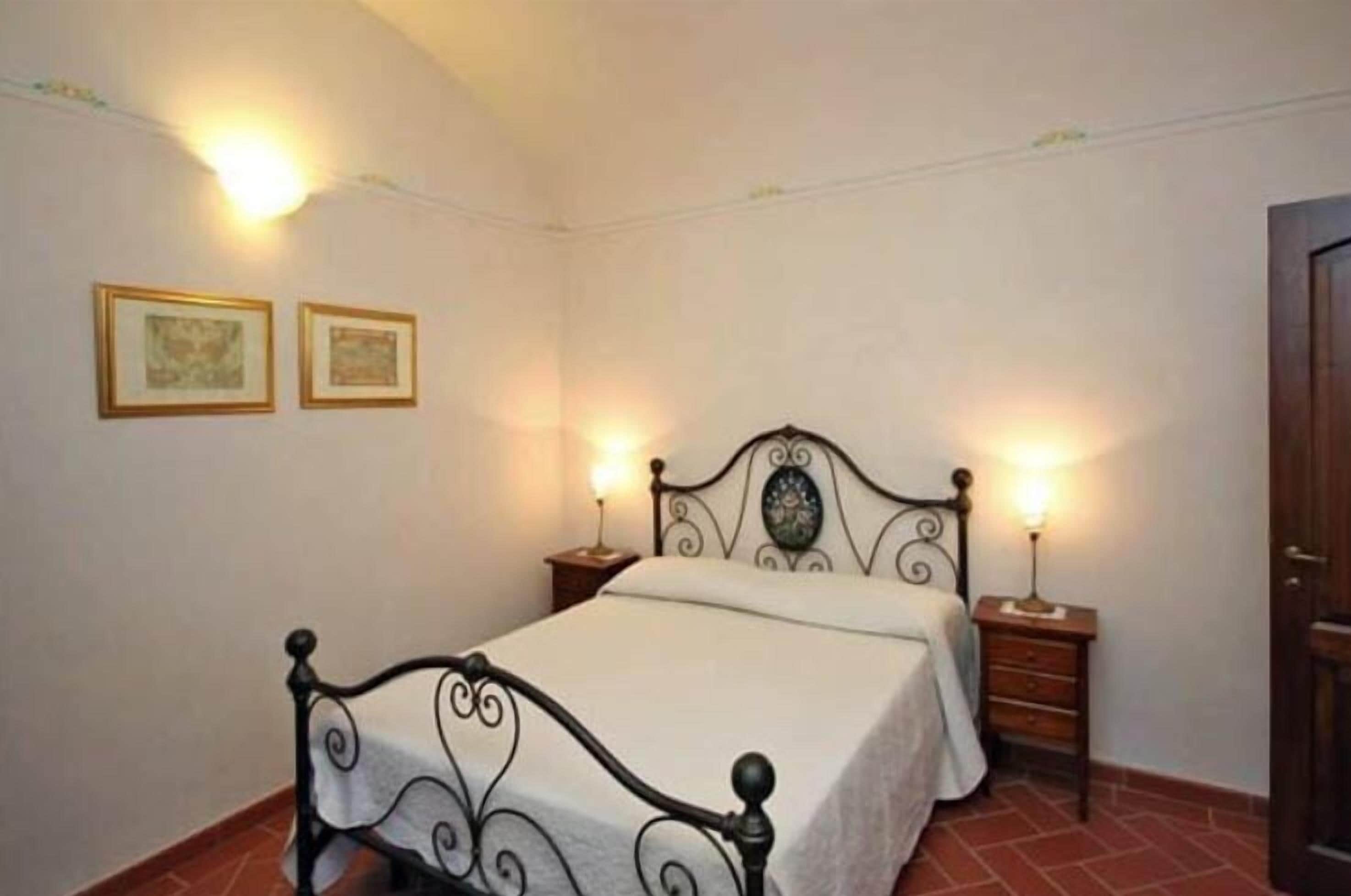 Un dormitorio con cama, dos mesitas de noche y dos lámparas de pared.