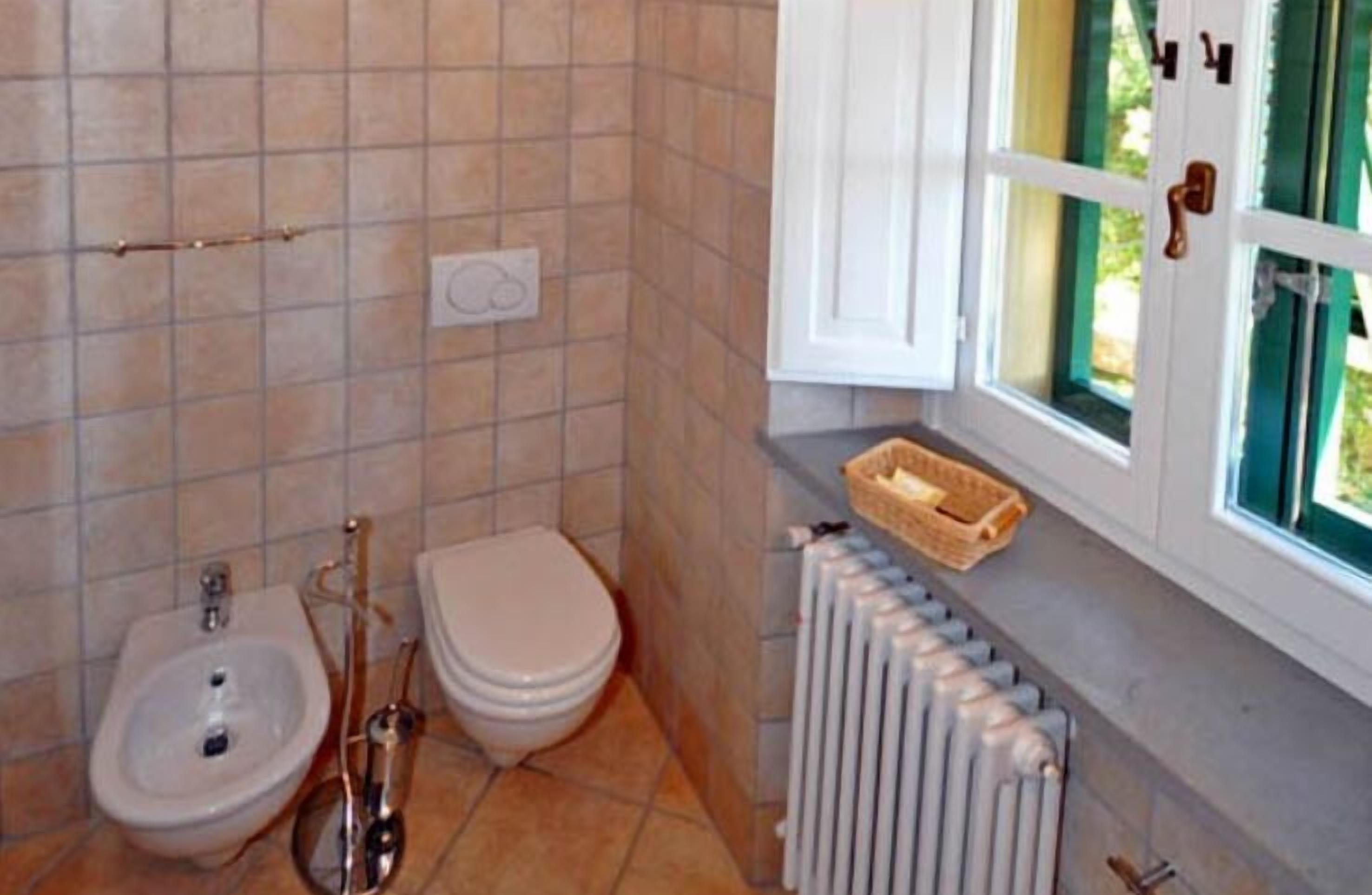 A bathroom with a bidet, toilet, and radiator.