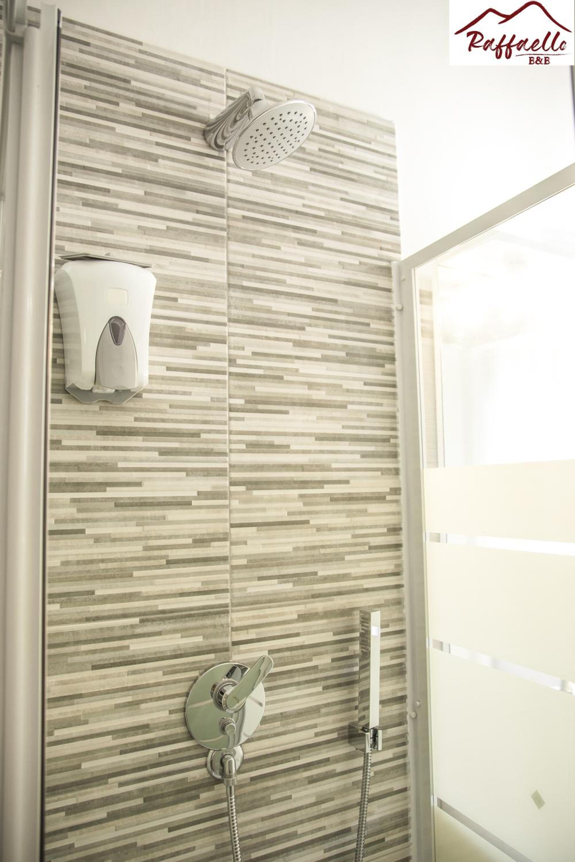 A shower area with a rain showerhead and a handheld showerhead, both mounted on a wall with a wood-like pattern.