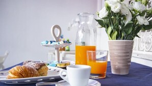 A breakfast setup with pastries, a pitcher of orange juice, a cup, and a vase of flowers. - B & B Raffaello (Terzigno)