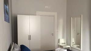 A bedroom with a wardrobe, a chair, a bed, and a mirror. - B & B Raffaello (Terzigno)