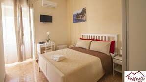 A bedroom with a bed, bedside tables, a TV, and a painting on the wall. - B & B Raffaello (Terzigno)