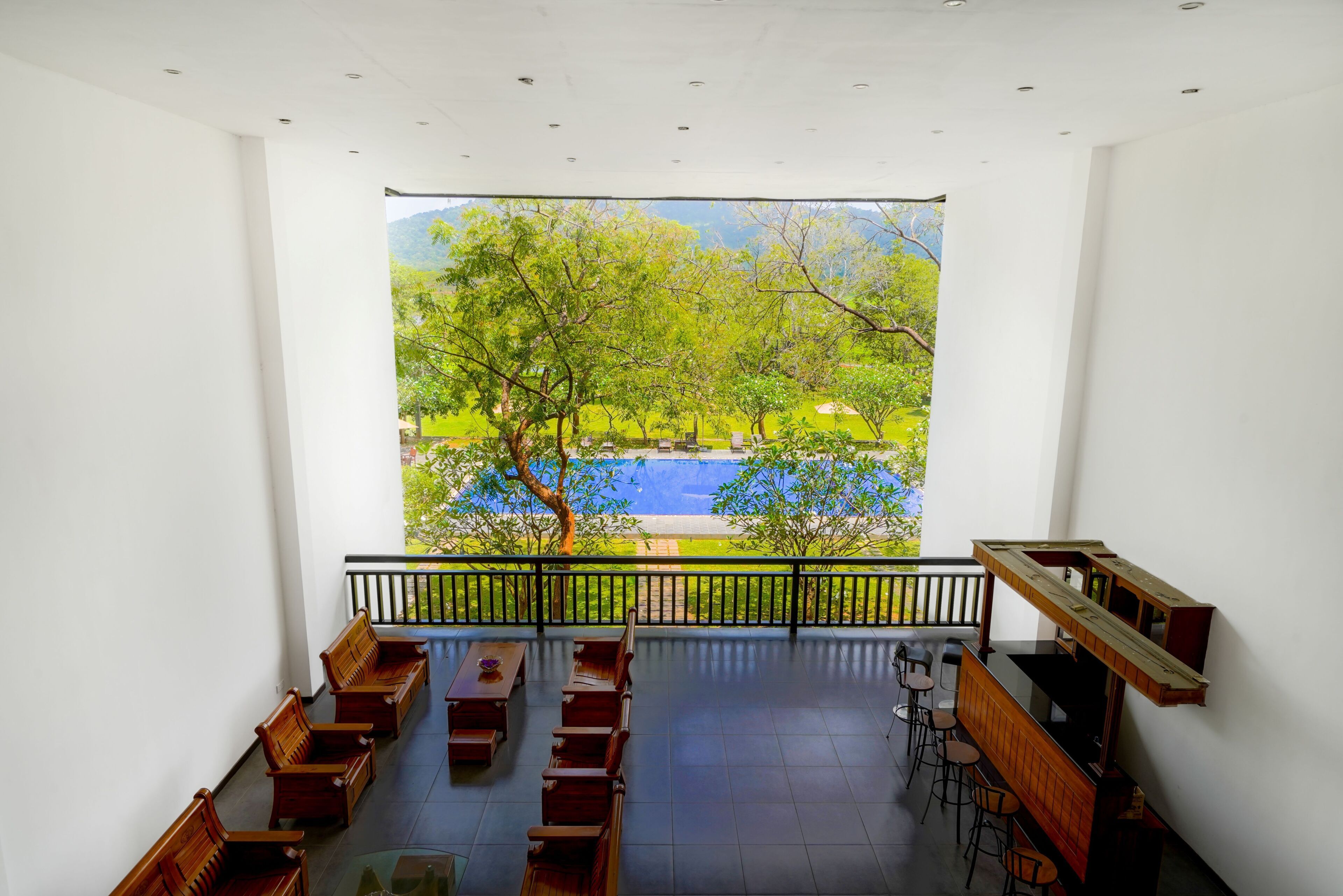 A room with a view of a park and a lake, wooden benches, and a table.