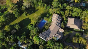 Zona residencial con piscina, varias casas y abundante vegetación.