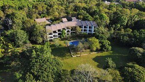 A multi-story building surrounded by lush greenery, with a swimming pool and a well-maintained lawn. - Grand Tamarind Lake (Kataragama)