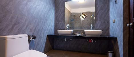 Un baño moderno con inodoro, dos lavamanos y un espejo.