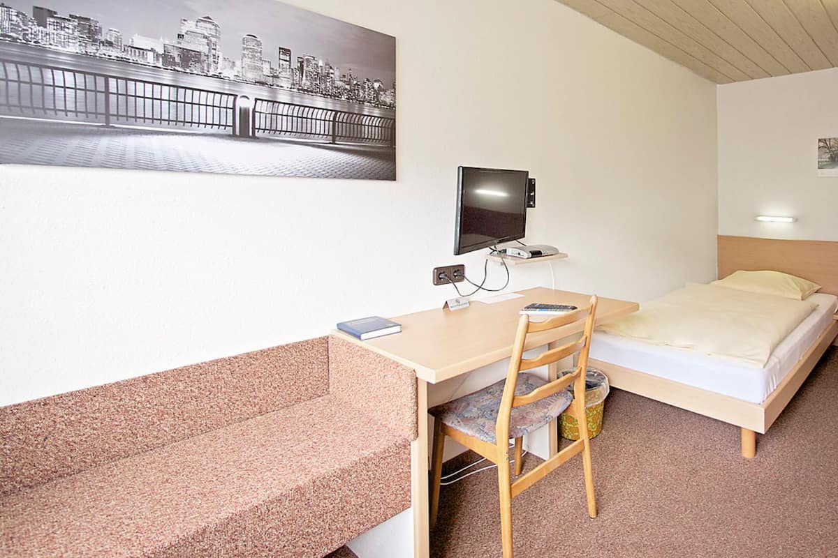 Une chambre d’hôtel équipée d’un bureau, d’une chaise, d’un lit et d’un téléviseur.