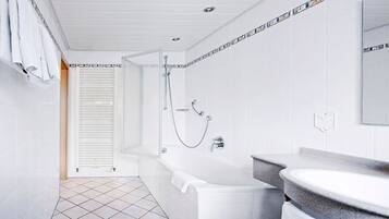 Une salle de bain moderne équipée d’une baignoire, d’une douche et d’un meuble-lavabo avec un évier.