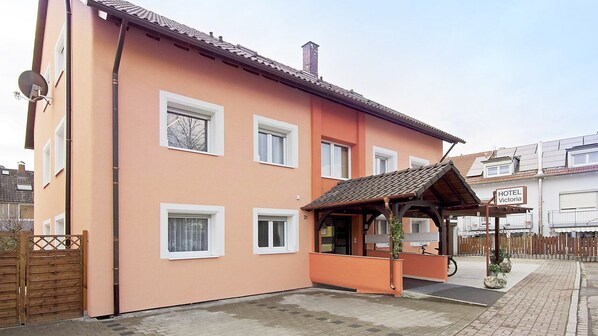A two-story building with a peach exterior, a covered entrance, and a sign indicating it is a hotel.