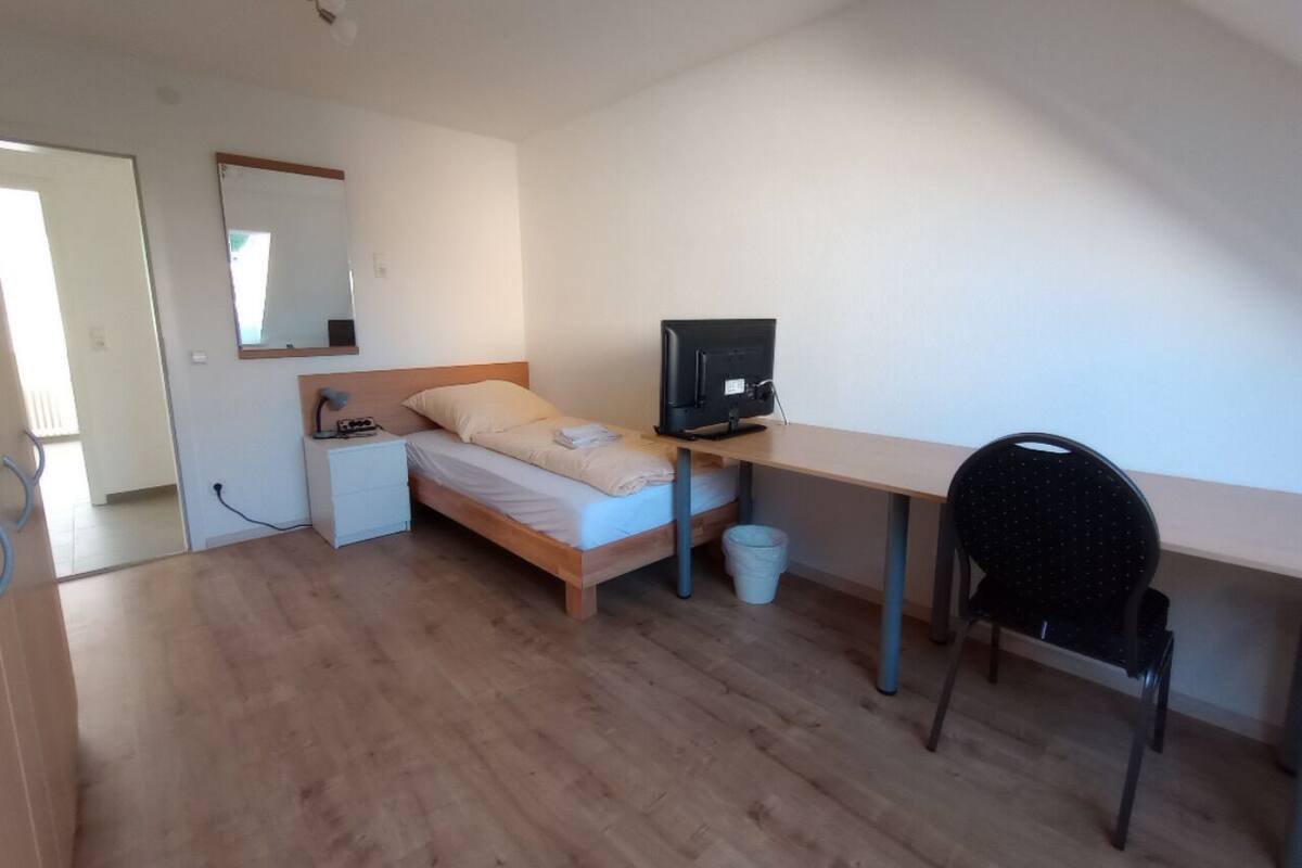 Une chambre à coucher comprenant un lit, un bureau, une chaise, une télévision et un miroir.