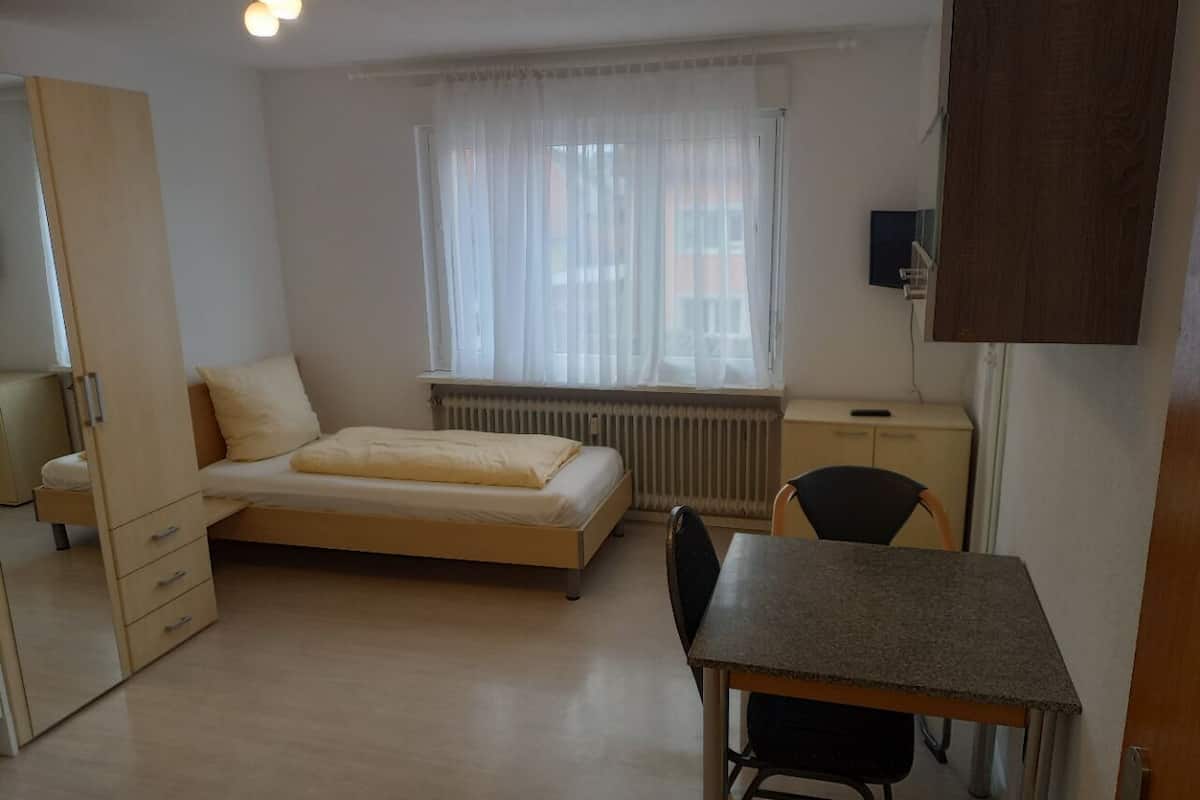 Une petite pièce comprenant un lit, un bureau et une chaise.